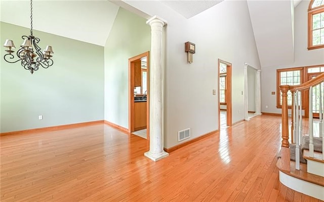 interior space featuring high vaulted ceiling, light hardwood / wood-style floors, plenty of natural light, and ornate columns