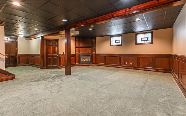 basement featuring light carpet and a paneled ceiling