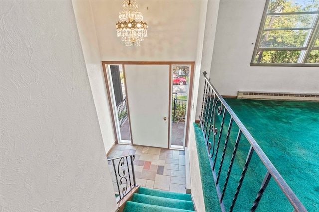 entryway featuring a high ceiling, baseboard heating, and a chandelier