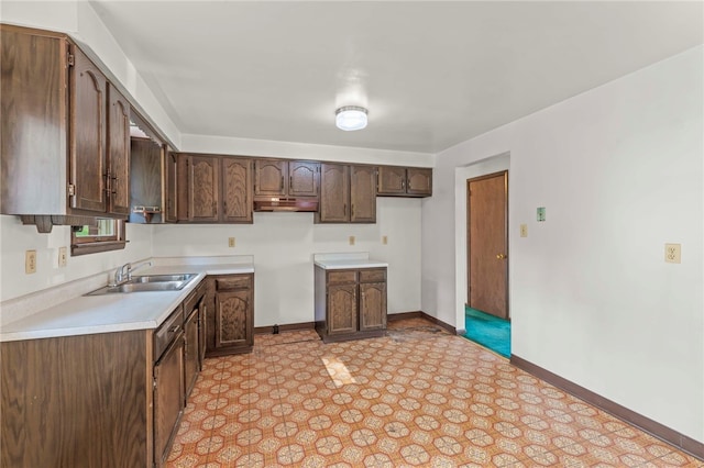 kitchen with dark brown cabinets, sink, and light tile patterned flooring