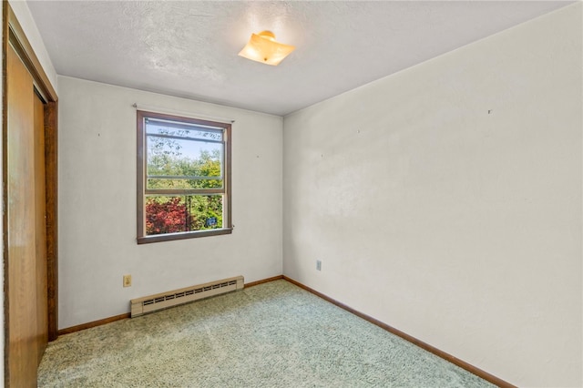 carpeted empty room featuring a textured ceiling and baseboard heating