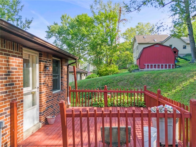 wooden deck featuring a lawn and an outbuilding