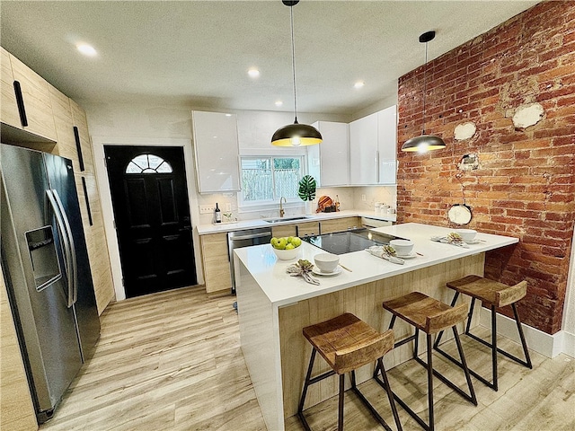 kitchen featuring decorative light fixtures, white cabinets, appliances with stainless steel finishes, and light wood-type flooring