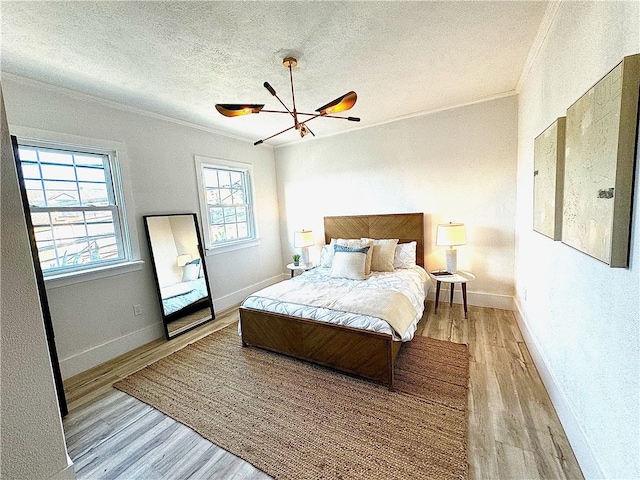 bedroom featuring light wood-type flooring, ceiling fan with notable chandelier, crown molding, and a textured ceiling