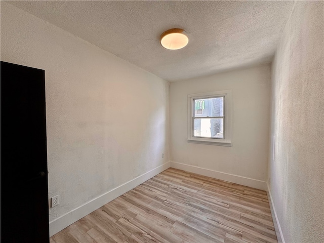 spare room with a textured ceiling and light hardwood / wood-style floors