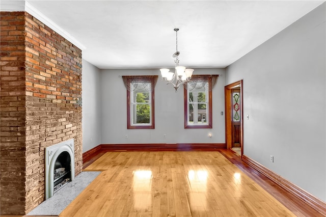 unfurnished living room featuring light hardwood / wood-style floors, a fireplace, a chandelier, and ornamental molding