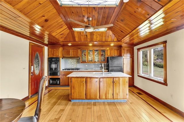 kitchen featuring a kitchen island with sink, light hardwood / wood-style flooring, black appliances, ceiling fan, and wooden ceiling