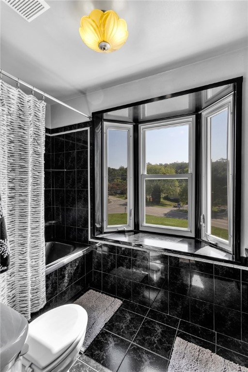 bathroom with toilet, a healthy amount of sunlight, and shower / bathtub combination with curtain