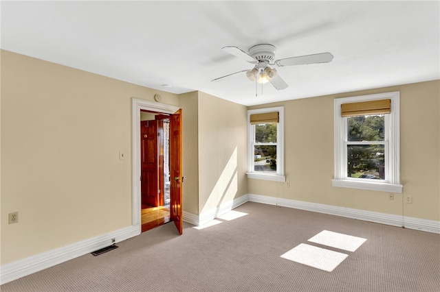 unfurnished room with ceiling fan, light colored carpet, and a healthy amount of sunlight