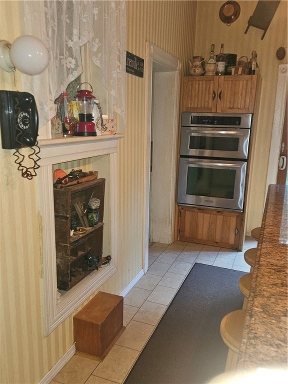 kitchen featuring stainless steel double oven and light tile patterned floors