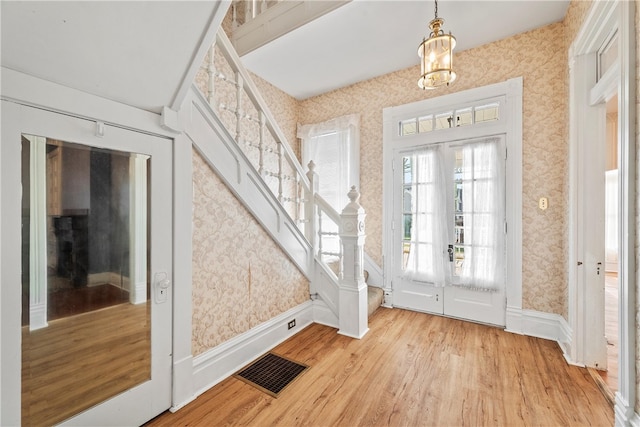 foyer entrance featuring light hardwood / wood-style flooring, french doors, and a notable chandelier