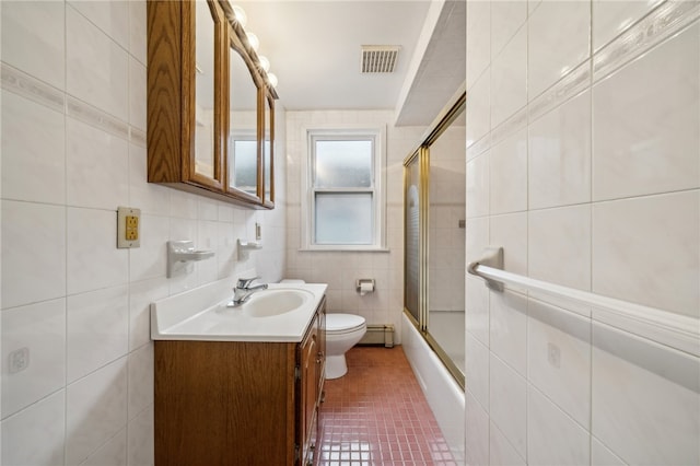 full bathroom featuring vanity, combined bath / shower with glass door, tile walls, toilet, and baseboard heating