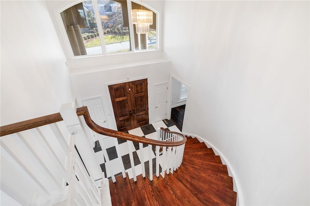 stairway with hardwood / wood-style flooring, a notable chandelier, and a towering ceiling