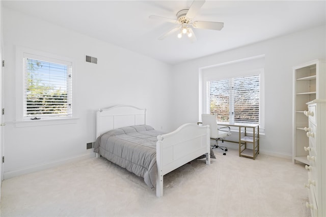 bedroom with ceiling fan, light carpet, and multiple windows