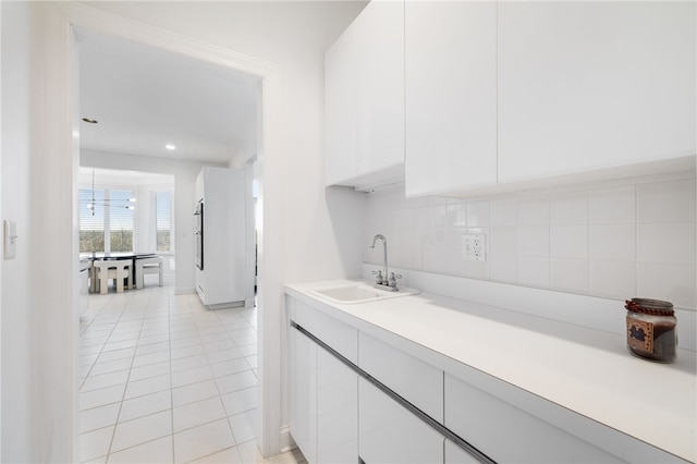 kitchen featuring light tile patterned flooring, sink, white cabinets, and decorative backsplash