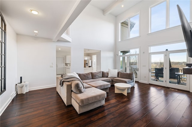 living room featuring a towering ceiling, dark hardwood / wood-style flooring, beamed ceiling, and french doors