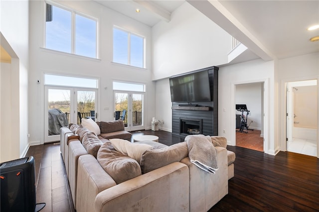 living room featuring a fireplace, dark hardwood / wood-style flooring, beamed ceiling, and french doors