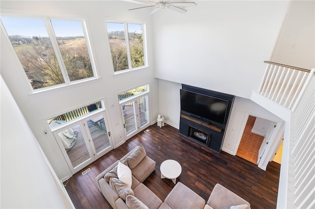 living room featuring plenty of natural light, ceiling fan, and dark wood-type flooring