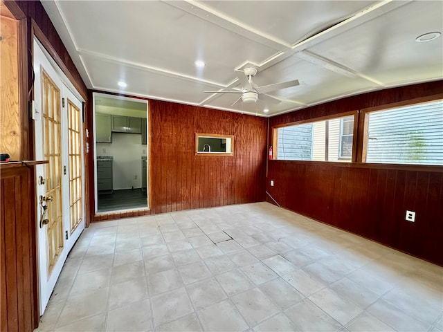 spare room featuring ceiling fan and wooden walls