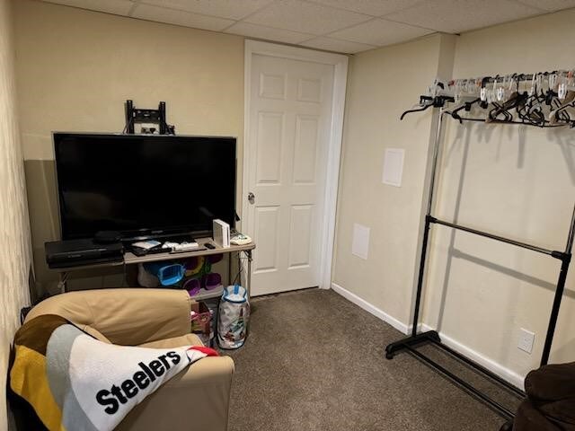 living room with a paneled ceiling and dark carpet