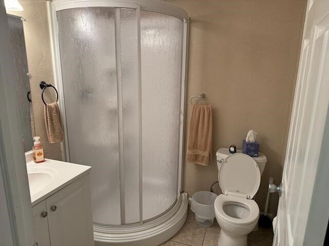 bathroom featuring vanity, toilet, a shower with shower door, and tile patterned flooring