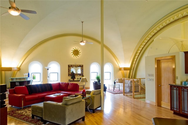 living room with light hardwood / wood-style floors, ceiling fan, and high vaulted ceiling