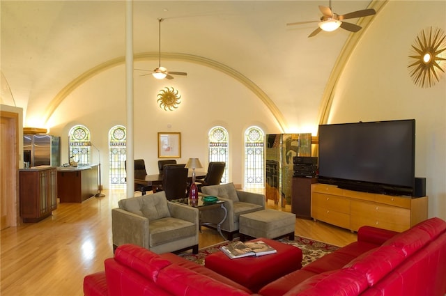 living room featuring light wood-type flooring, ornamental molding, ceiling fan, and high vaulted ceiling