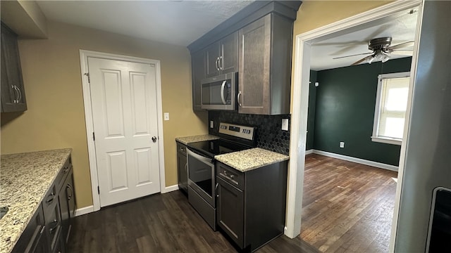 kitchen with ceiling fan, dark wood-type flooring, light stone counters, backsplash, and appliances with stainless steel finishes