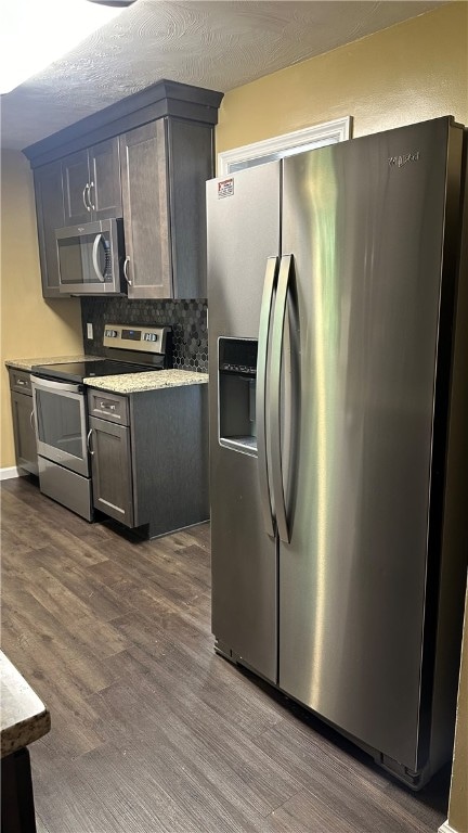 kitchen with backsplash, dark wood-type flooring, appliances with stainless steel finishes, and a textured ceiling