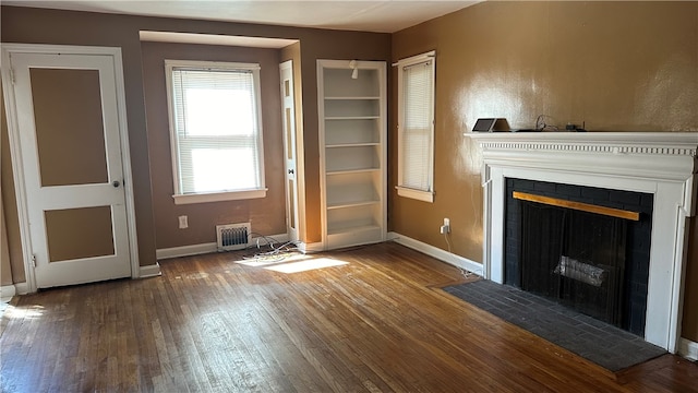 unfurnished living room with a tile fireplace and dark hardwood / wood-style flooring