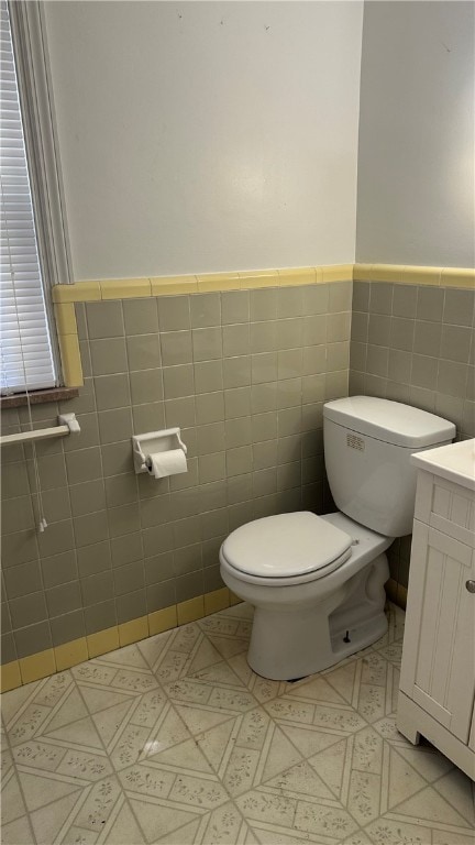 bathroom featuring vanity, toilet, and tile walls