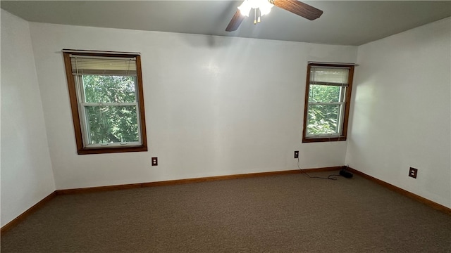 spare room with ceiling fan, a healthy amount of sunlight, and dark colored carpet