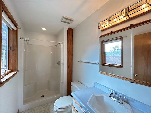 bathroom featuring a healthy amount of sunlight, toilet, a shower, and vanity