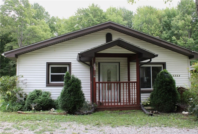 bungalow with covered porch and a front lawn