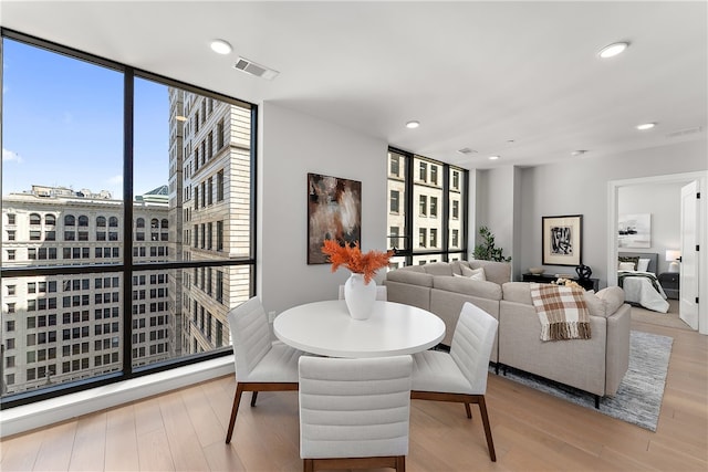 dining space with floor to ceiling windows and light hardwood / wood-style floors