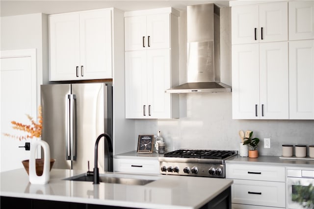 kitchen featuring wall chimney exhaust hood, white cabinetry, and stainless steel refrigerator