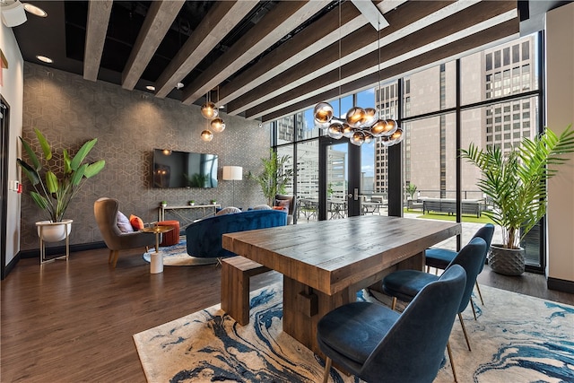 dining area featuring dark wood-type flooring, ceiling fan with notable chandelier, expansive windows, and beamed ceiling