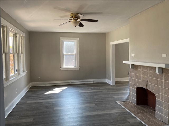 unfurnished living room with ceiling fan, a tiled fireplace, dark hardwood / wood-style flooring, and a wealth of natural light