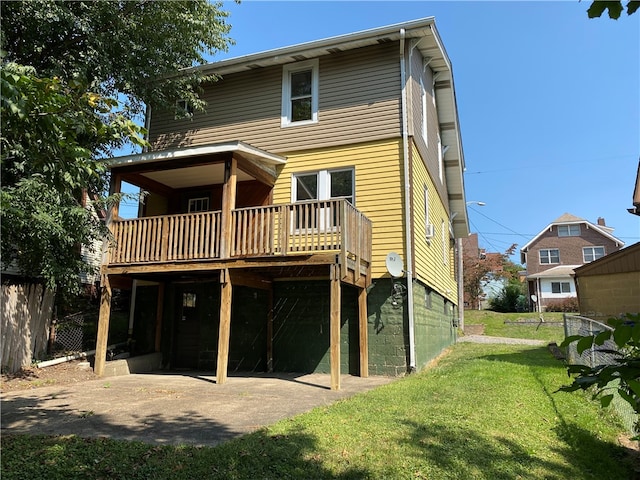 rear view of property featuring a garage, a wooden deck, and a yard