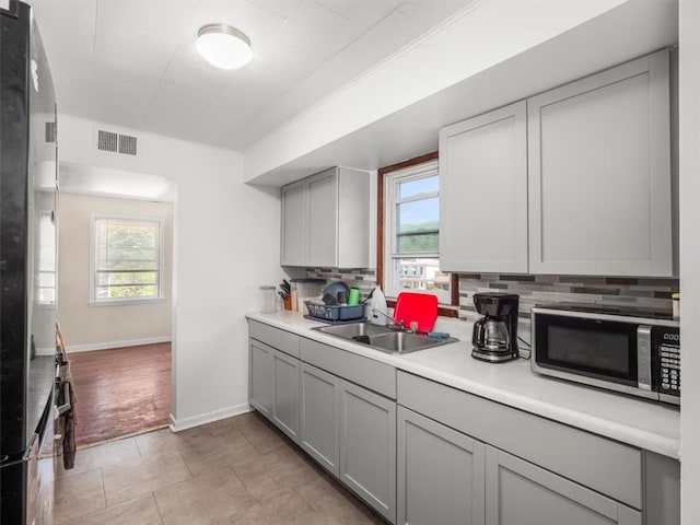 kitchen with gray cabinets, a wealth of natural light, sink, and light tile patterned flooring