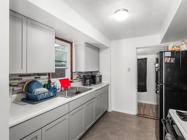 kitchen featuring gas range oven, tasteful backsplash, sink, gray cabinets, and light wood-type flooring