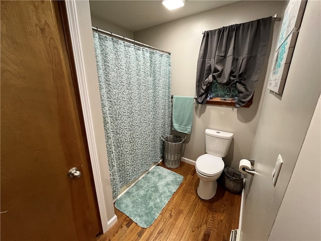 bathroom featuring curtained shower, toilet, and hardwood / wood-style flooring