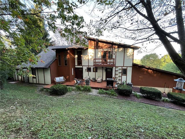 rear view of property featuring a balcony, a lawn, and a deck