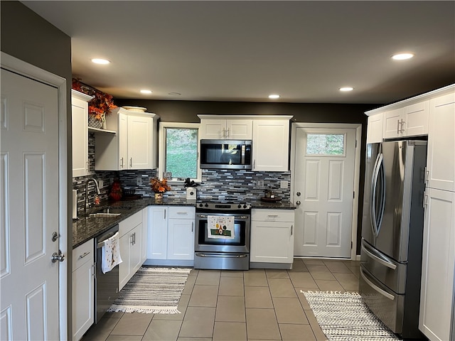 kitchen with dark stone countertops, backsplash, stainless steel appliances, sink, and white cabinets