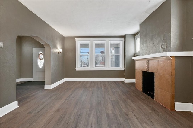 unfurnished living room featuring dark hardwood / wood-style flooring and a tiled fireplace