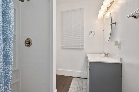 bathroom with walk in shower, hardwood / wood-style flooring, and vanity