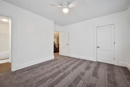 carpeted spare room featuring ceiling fan