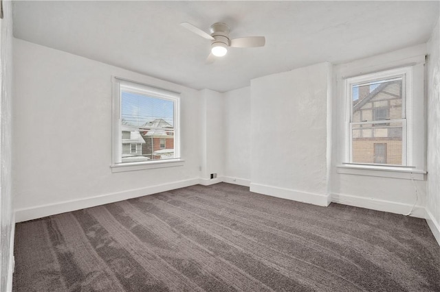 unfurnished room with ceiling fan, dark carpet, and a wealth of natural light