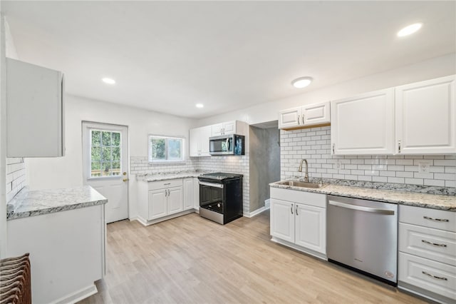 kitchen featuring white cabinetry, light hardwood / wood-style flooring, tasteful backsplash, stainless steel appliances, and sink