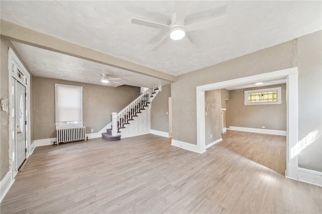 basement with ceiling fan, radiator, and light hardwood / wood-style floors